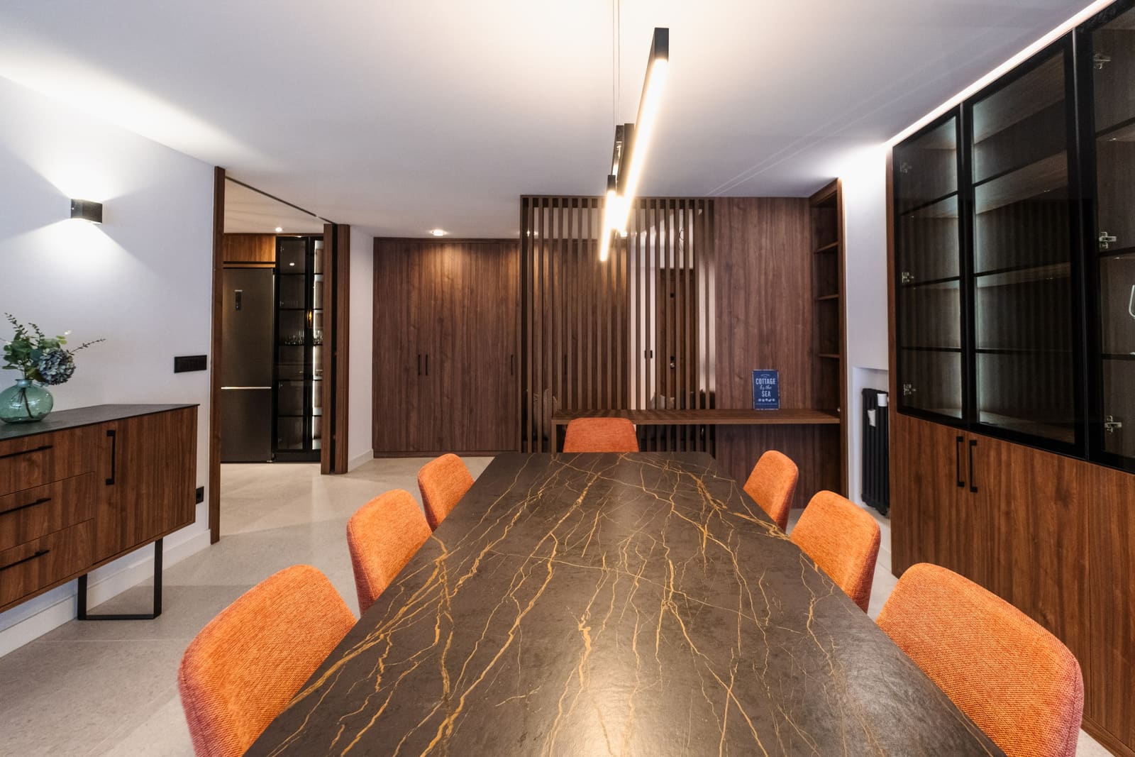 Comedor con mesa de porcelánico y sillas naranjas en una vivienda reformada